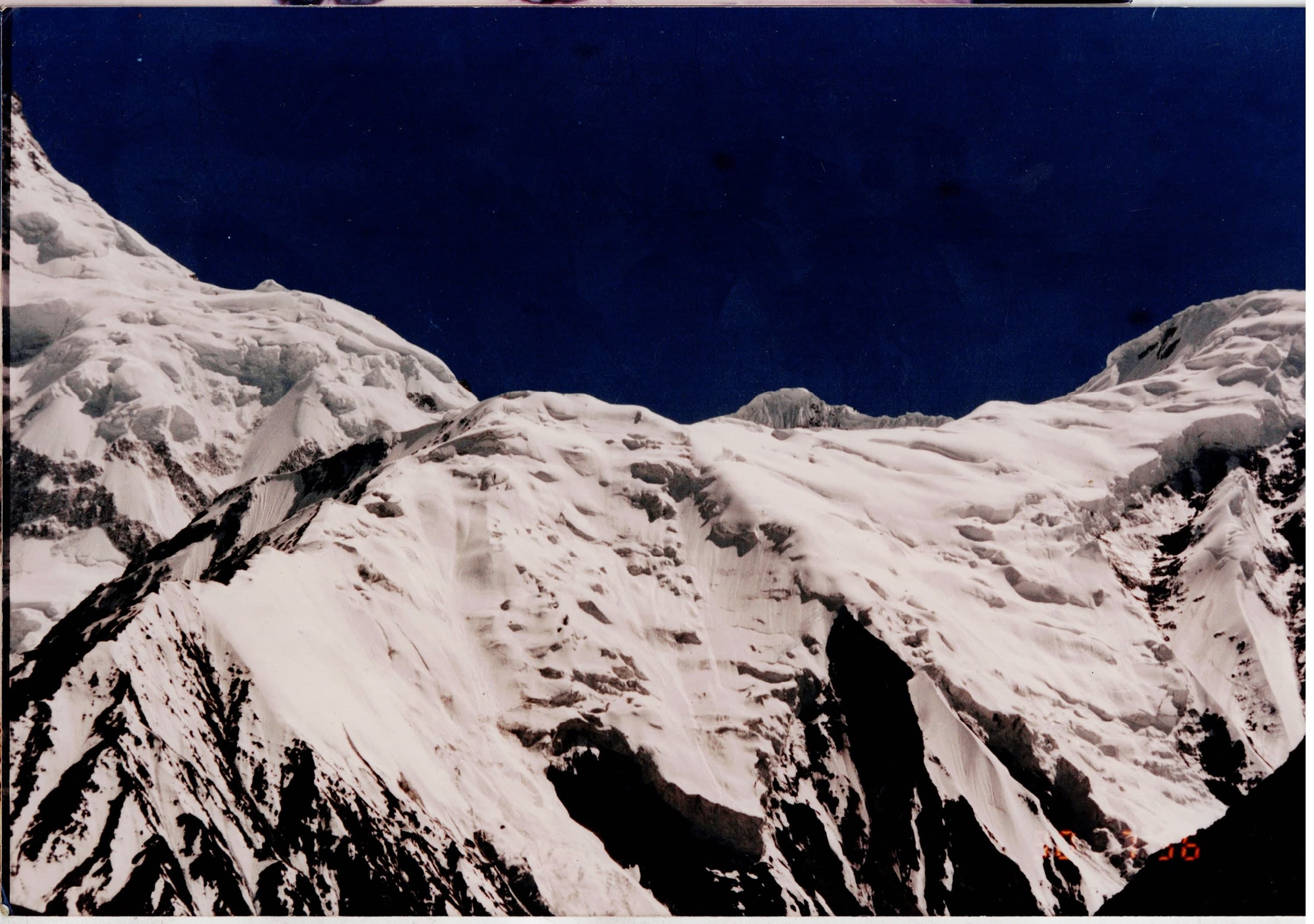 Snow-covered ridge and hanging glaciers against a dark blue high-altitude sky