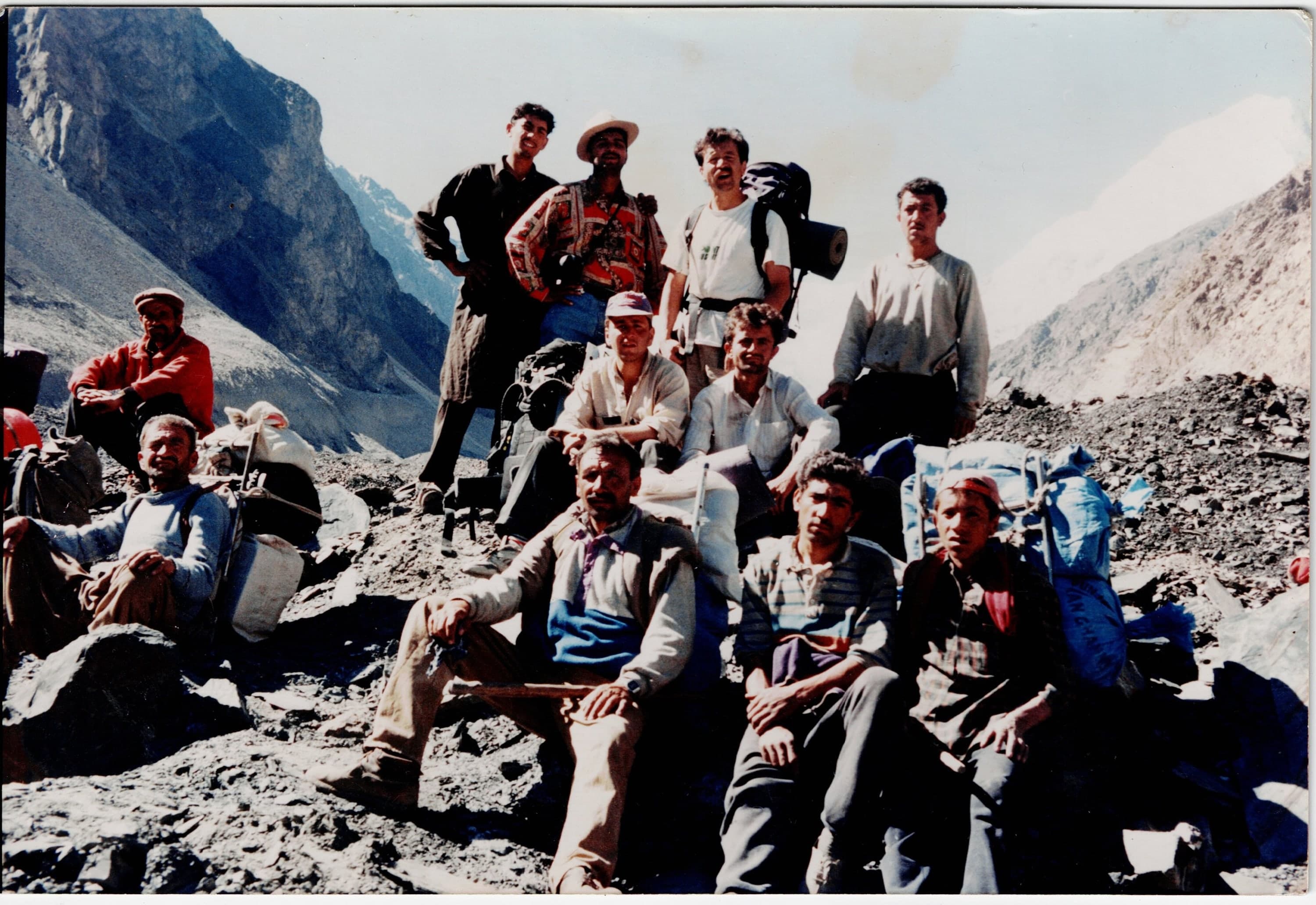 Porters and trekkers resting with their loads on the moraine of a Karakoram glacier