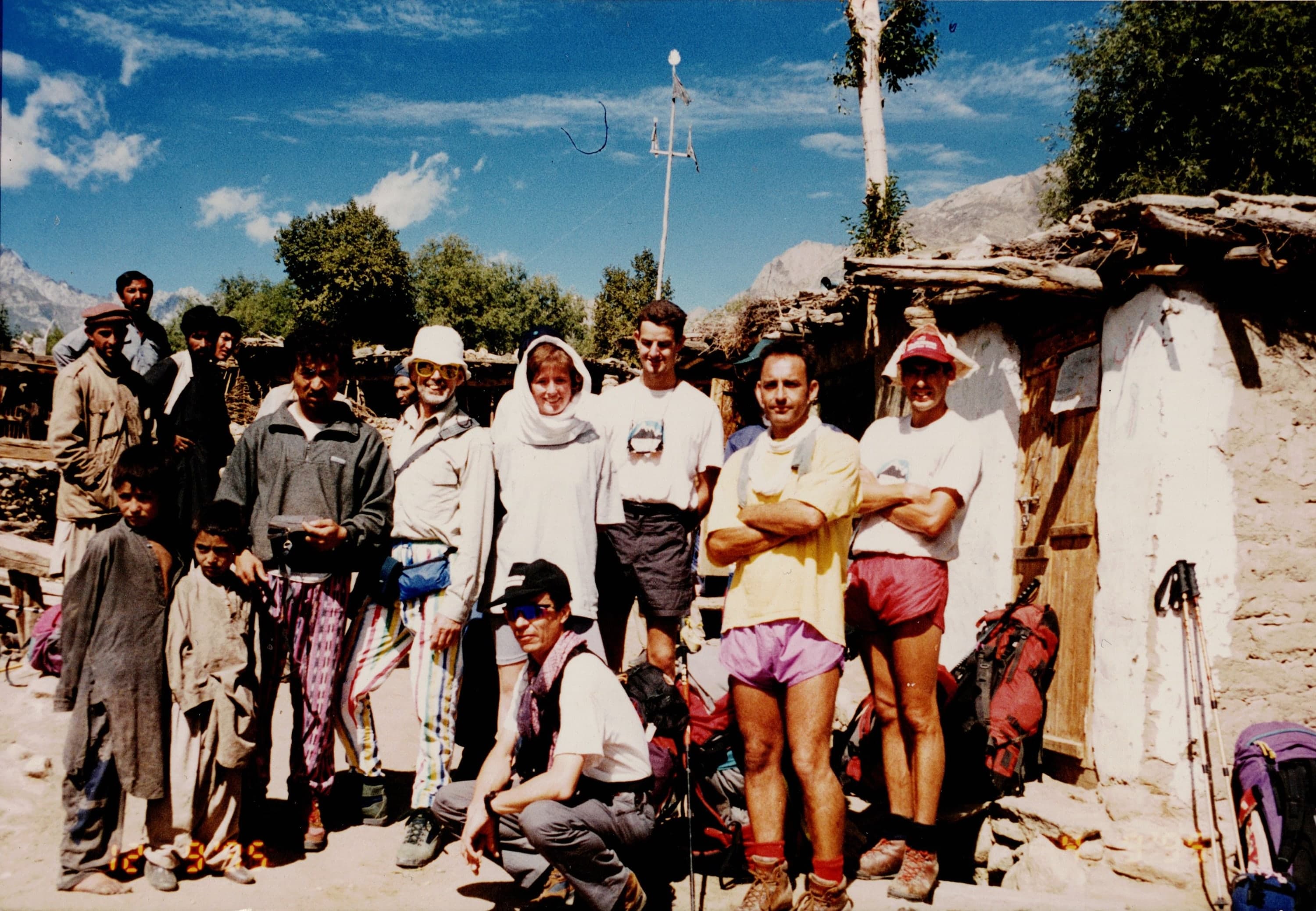 Foreign trekkers and local children outside a stone house in a Gilgit-Baltistan mountain village