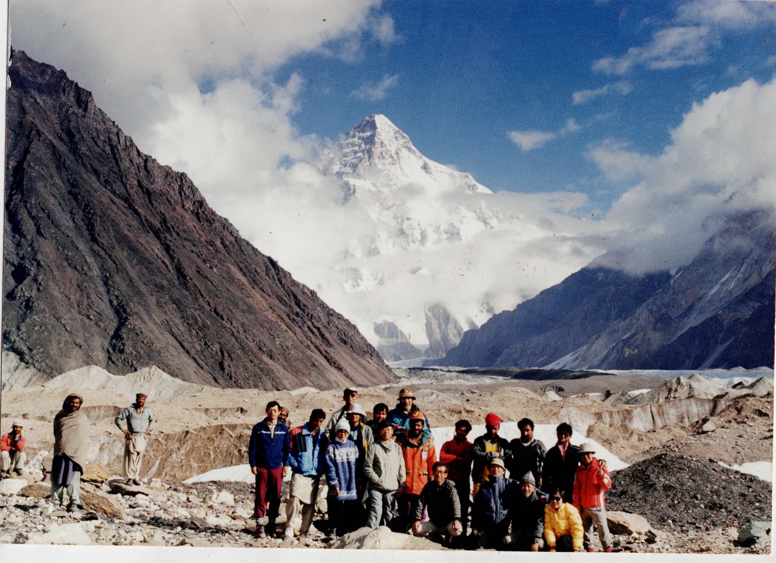 Large expedition group of porters, guides and foreign trekkers on the Baltoro Glacier with K2 behind